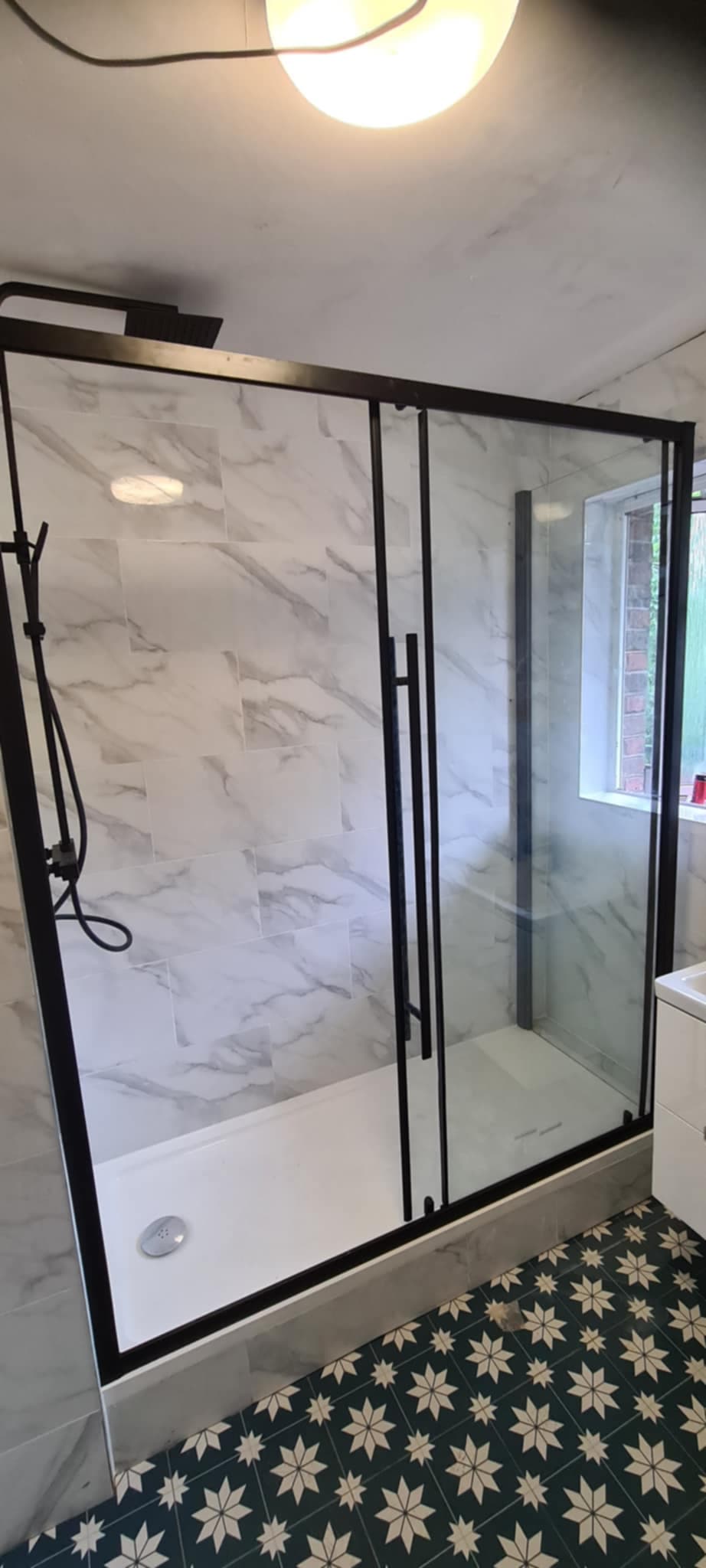 Black frame walk-in shower enclosure with patterned floor tiles