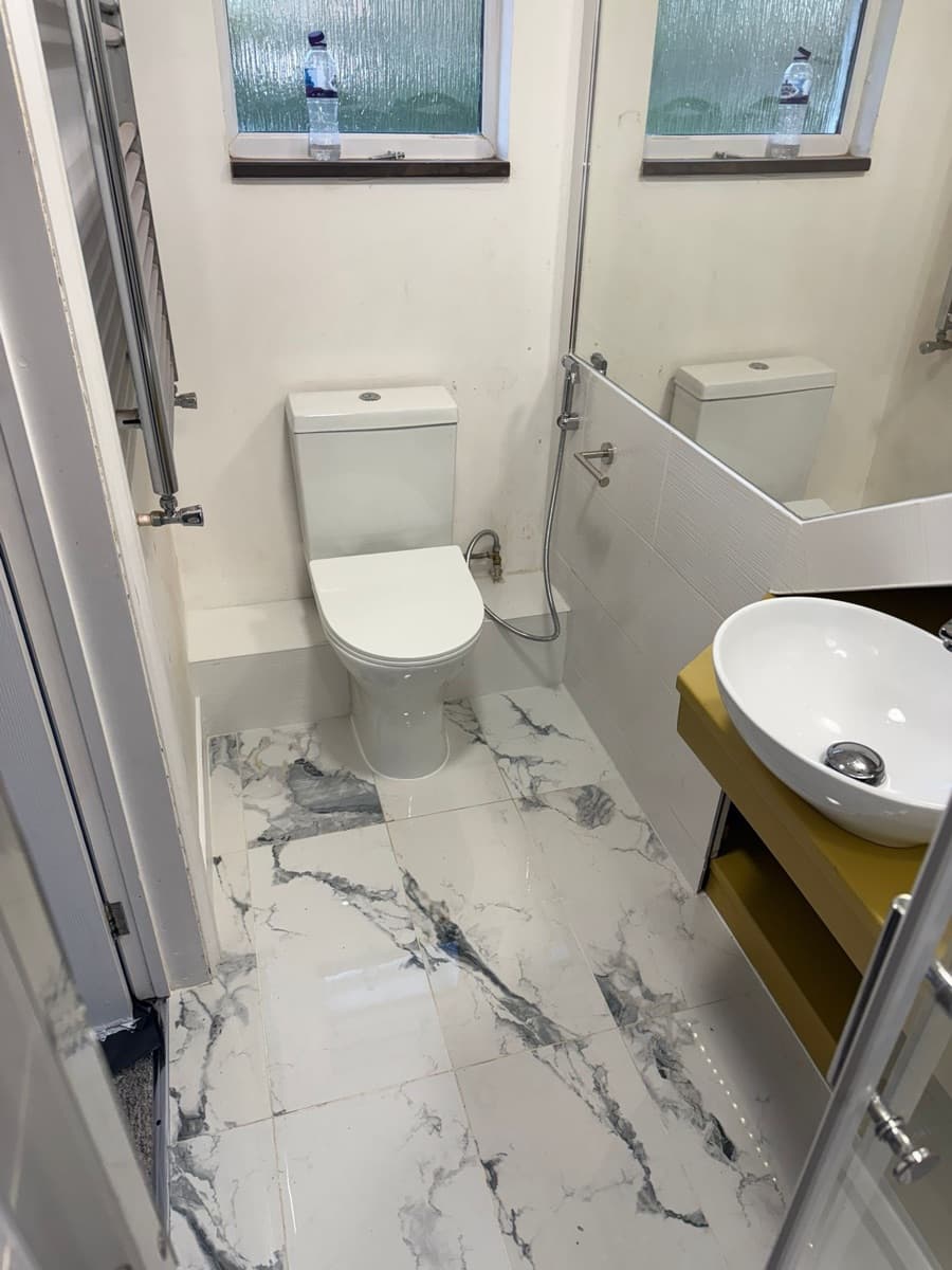 Compact bathroom renovation with marble floor tiles and vessel basin