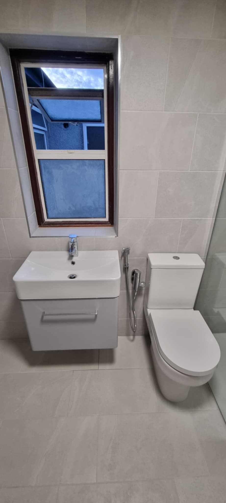 Cream tile bathroom with wall hung vanity and toilet
