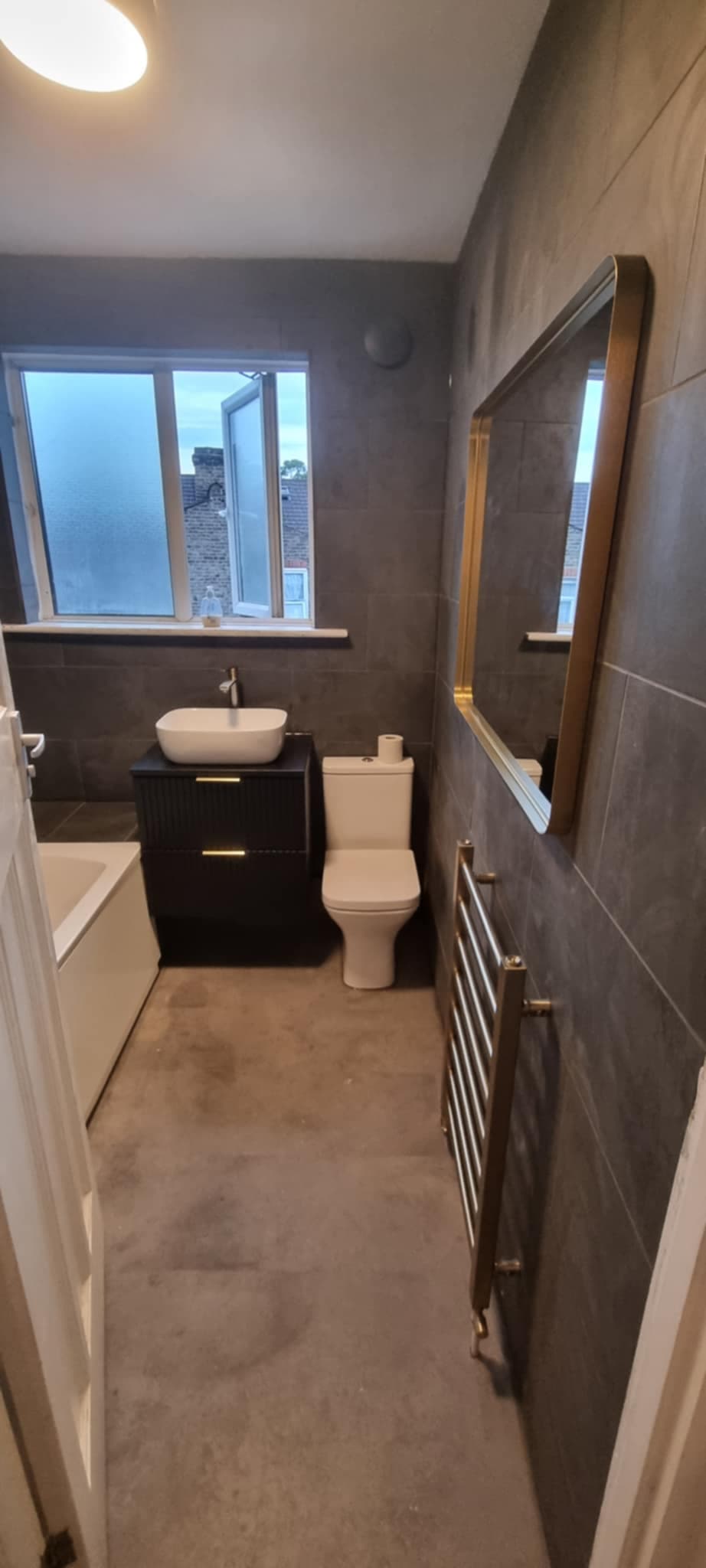 Dark tile bathroom with gold accents and vessel basin