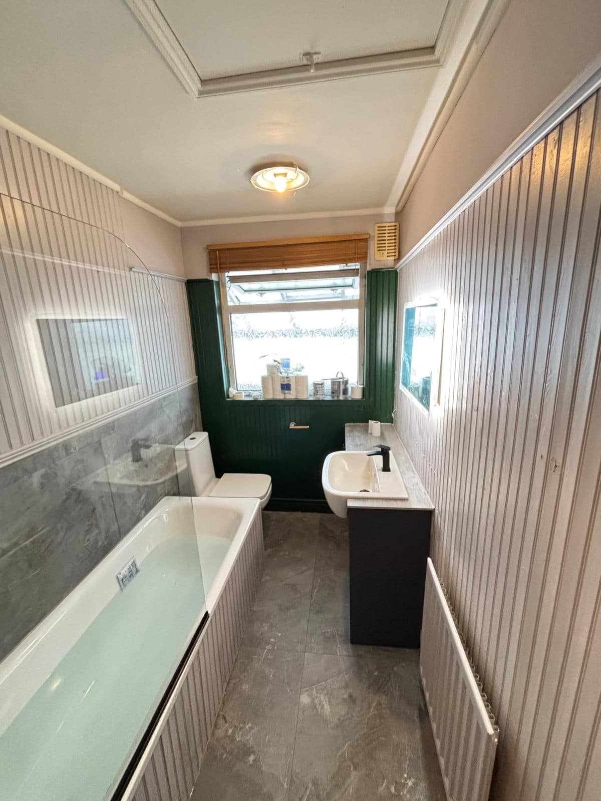 Green panelled bathroom with marble tiles