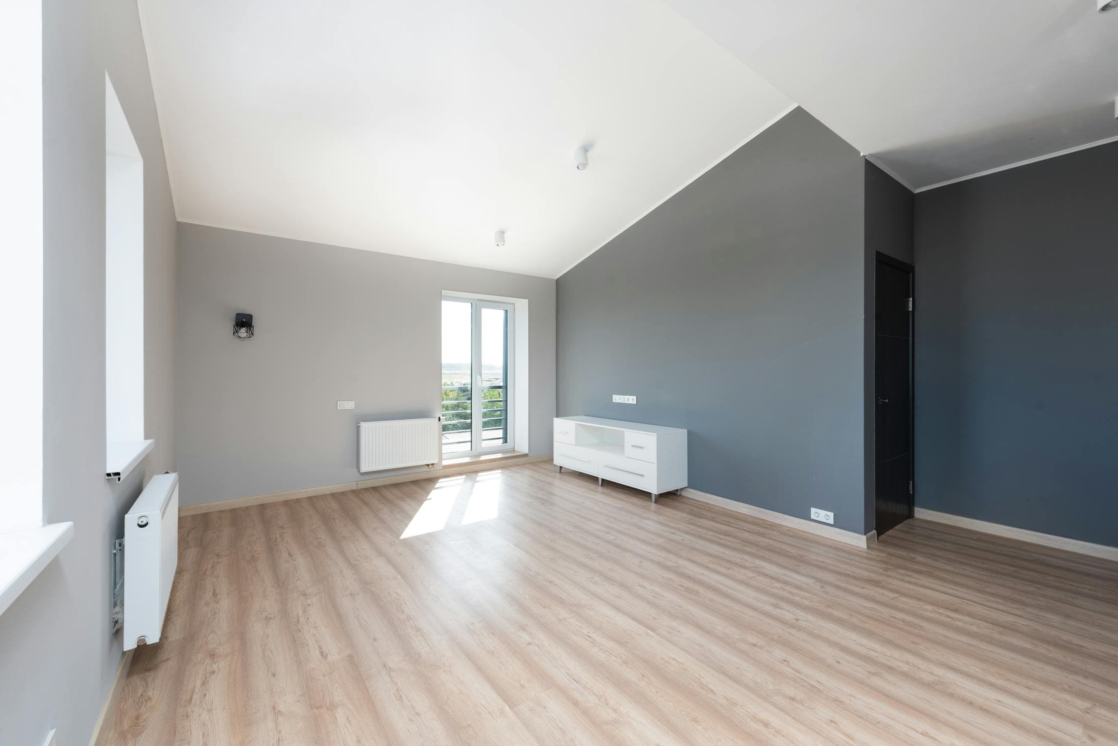 Freshly painted room with grey accent wall and hardwood floors