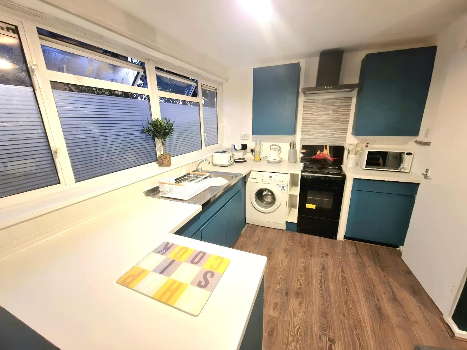 Teal kitchen with white worktops
