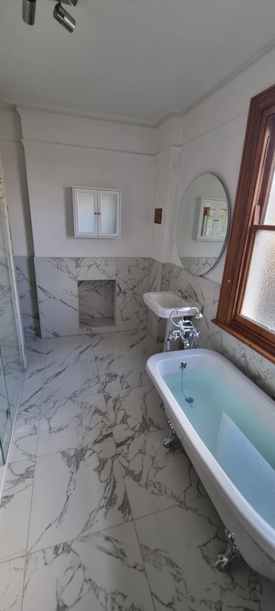 Freestanding clawfoot bath in marble bathroom renovation