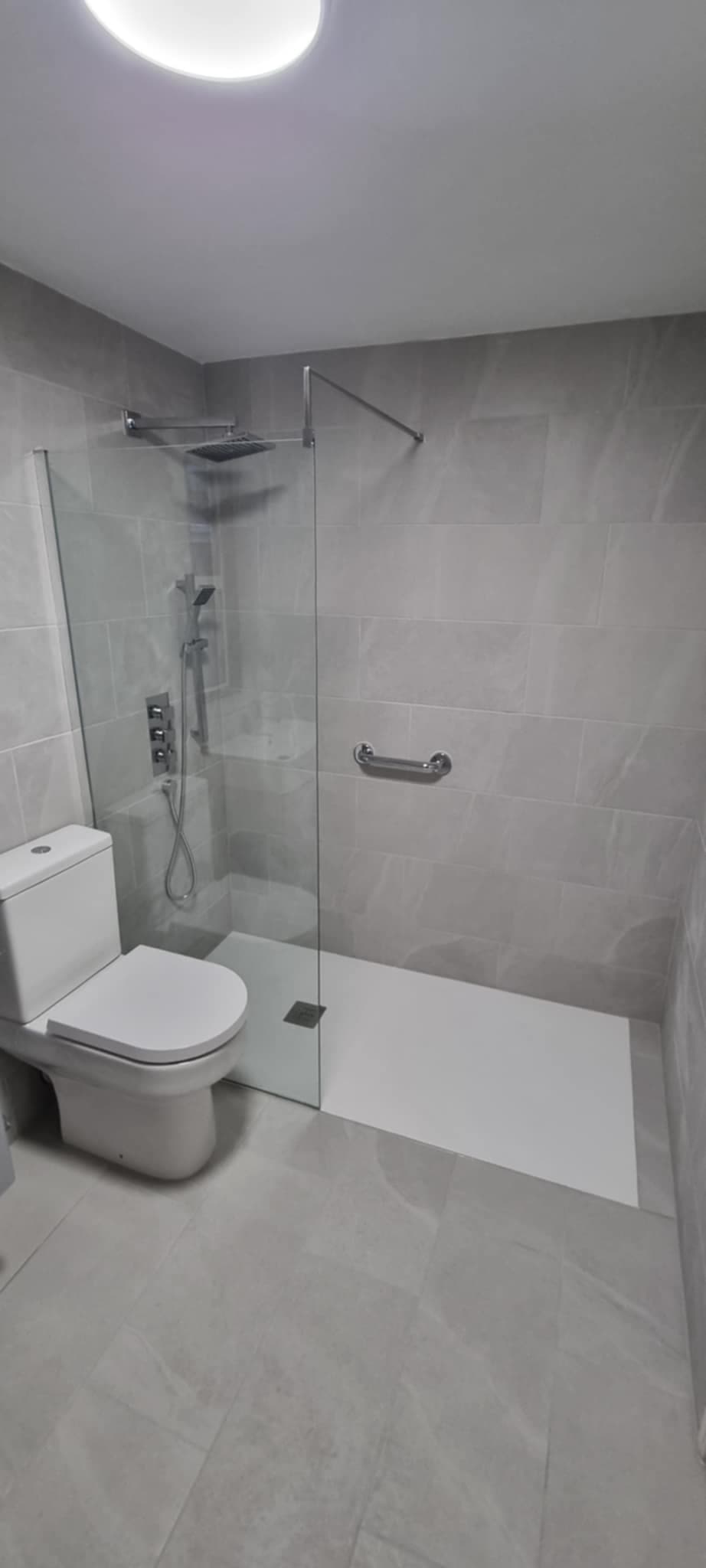 Modern walk-in shower with glass panel and rain head