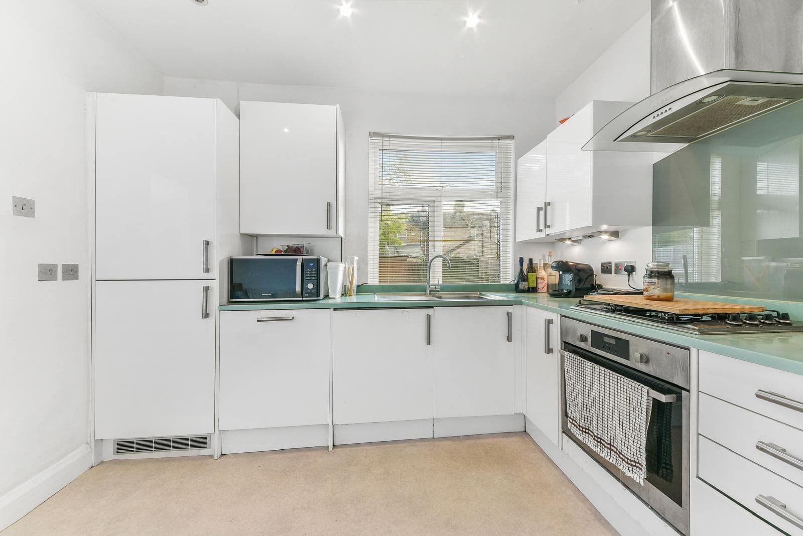 Modern white kitchen with glass splashback and green worktop